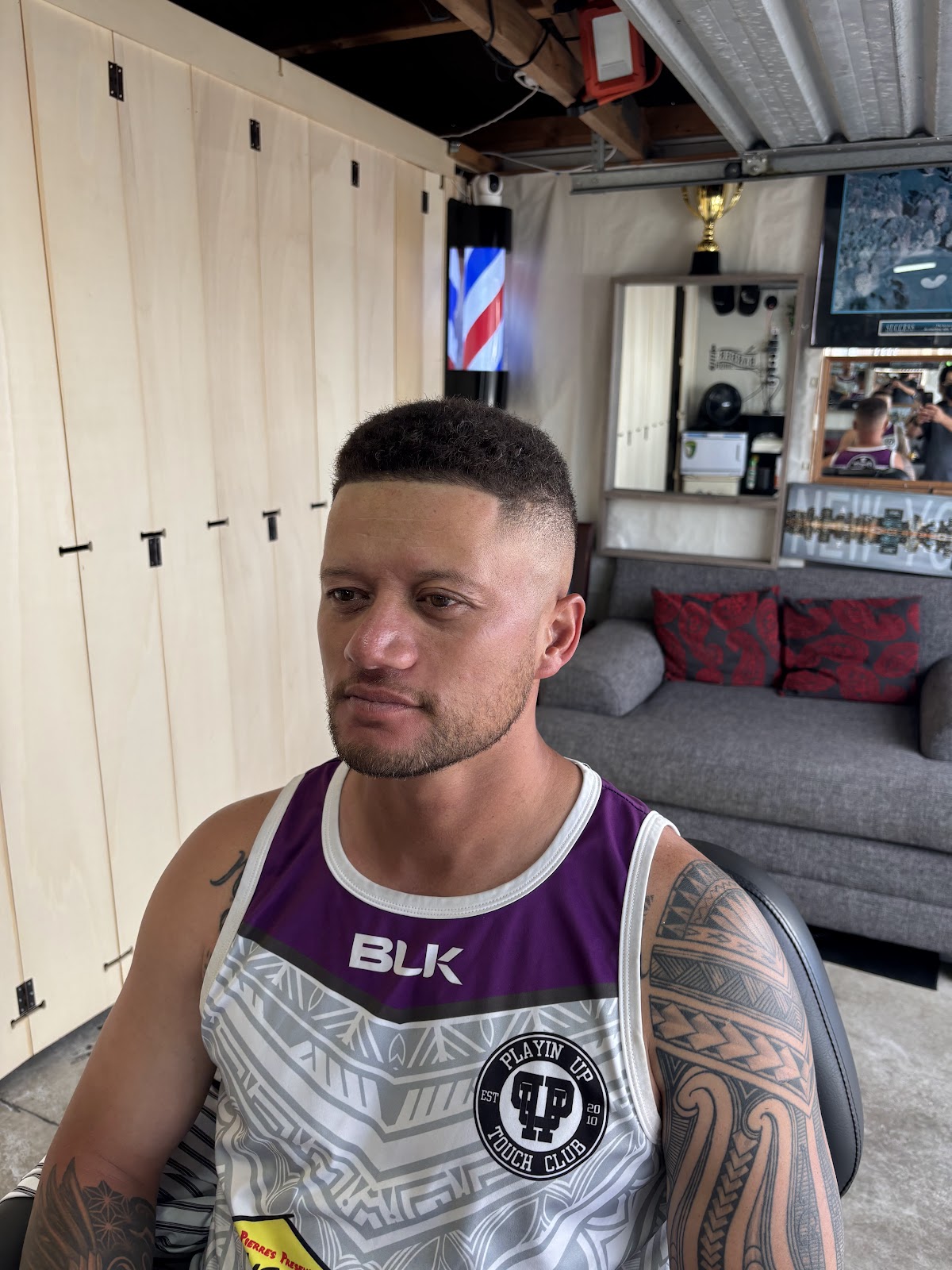 Client with a fresh fade in the studio, barber pole behind